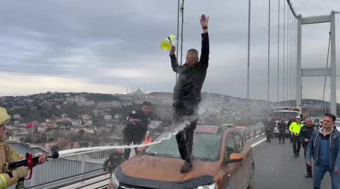 Otomobilin üzerine çıkıp benzin döken şahsa itfaiyeciden ‘su sıkma’ müdahalesi